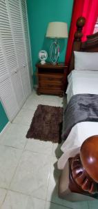 a bedroom with a bed and a table with a lamp at Finest Accommodation 75 Blossom, The Orchards innswood St Catherine in Spanish Town