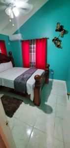 1 dormitorio con 1 cama con paredes rojas y azules en Finest Accommodation 75 Blossom, The Orchards innswood St Catherine en Spanish Town