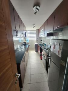 a kitchen with wooden cabinets and a black counter top at Playa Huayquique, primera linea in Iquique