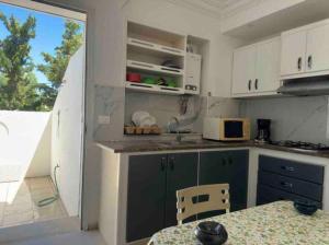 een keuken met groene en witte kasten en een tafel bij Duplex El mansoura A1 in Kelibia