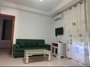 een woonkamer met een groene bank en een salontafel bij Duplex El mansoura A1 in Kelibia