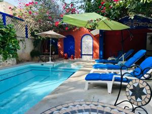 a pool with blue chairs and an umbrella and a swimming pool at Casa Tres Colibries in Mérida