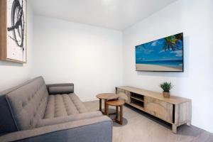 a living room with a couch and a tv on a wall at 2BR Luxury Central Palm Beach Apartment (Best Location!) in Gold Coast