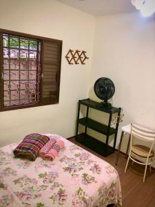 ein Schlafzimmer mit einem Bett mit einer rosa Decke und einem Fenster in der Unterkunft Quarto confortável lago igapó in Londrina