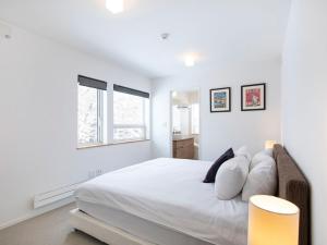 a white bedroom with a large bed with pillows at Ajisai Chalet in Niseko