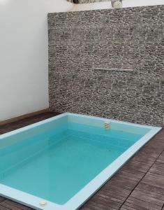 een zwembad met blauw water voor een bakstenen muur bij Casa Punta Hermosa Piscina Terraza in Punta Hermosa