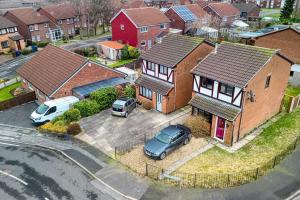 een huis met twee auto's geparkeerd op een parkeerplaats bij Large cosy house w/driveway 7pax in Radcliffe