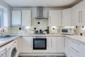 a white kitchen with white cabinets and a dishwasher at Large cosy house w/driveway 7pax in Radcliffe