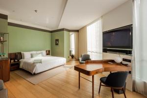 - une chambre avec un lit, un bureau et une télévision dans l'établissement The Sukhothai Shanghai, à Shanghai