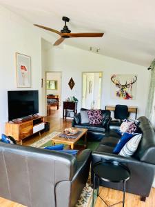 sala de estar con muebles de cuero negro y TV de pantalla plana en Don Valley Lodge en Launching Place