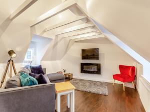 a living room with a couch and a red chair at Vectis Cottage in Inverness