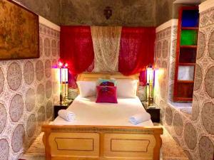 a bedroom with a bed with red curtains and two lamps at Dar El Jazouli in Marrakesh