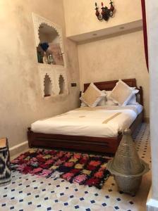 a bedroom with a bed with a rug on the floor at Dar El Jazouli in Marrakesh