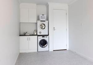 a laundry room with a washer and a washing machine at Luxury home in Christies Beach with King Bed, NBN, Netflix, 3Bed 2Bath in Christies Beach