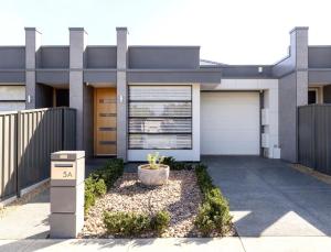 a house with a garage door and a driveway at Luxury home in Christies Beach with King Bed, NBN, Netflix, 3Bed 2Bath in Christies Beach