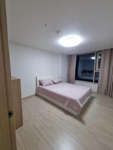 a white bedroom with a bed and a window at Luxury ocean view in Busan