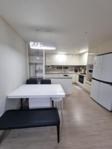 a white kitchen with a white table and chairs at Luxury ocean view in Busan