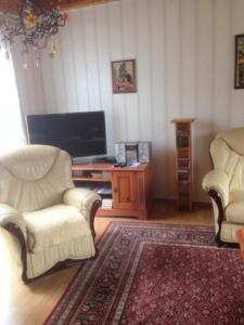 a living room with two chairs and a television at Bungalow mit Kamin in Ribnitz-Damgarten in Ribnitz-Damgarten