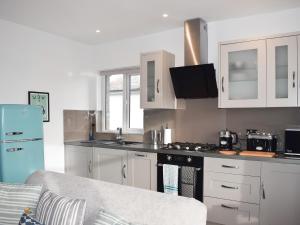uma cozinha com armários brancos e um frigorífico azul em Sea Breeze Apartment em Goring by Sea