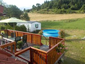 eine Holzterrasse mit einem Sonnenschirm und einer Badewanne in der Unterkunft Eine Ferienwohnung in einer grünen und waldreichen Umgebung in Slovenj Gradec
