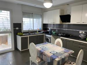 a kitchen with a table and some chairs and a table and a kitchen at Villa Mina résidence in Kelibia
