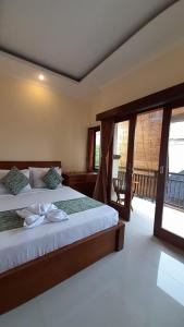 a bedroom with a large bed and a balcony at Nugraha Guesthouse 1 in Ubud