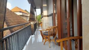 un balcón con mesa y 2 sillas. en Nugraha Guesthouse 1, en Ubud