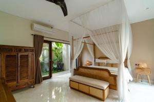 a bedroom with a bed with a mosquito net at La Rose Villas and Suites Camp Canggu in Canggu