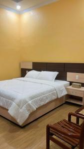 a bedroom with a large white bed and a chair at Abaka Hotel in Lamglumpang