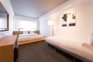two beds in a room with white walls and a window at Hotel Mystays Premier Hamamatsucho in Tokyo