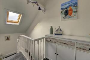 a white nursery with a crib and a window at Kraken Cottage in Bridlington