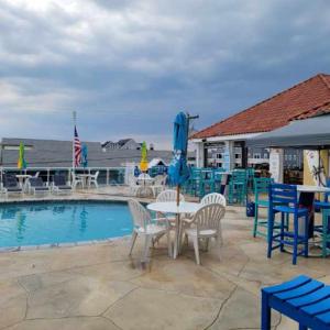 eine Terrasse mit einem Tisch, Stühlen und einem Pool in der Unterkunft Champagne Isle Resort Unit 107 in Wildwood