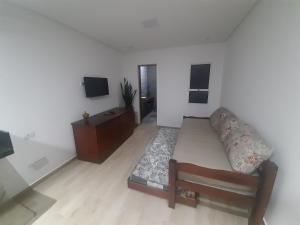 a living room with a couch and a tv at Loft Enseada in Guarujá