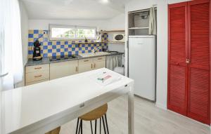cocina con puertas rojas y nevera blanca en Cozy Home In St Paul Trois Chateaux With Outdoor Swimming Pool, en Saint-Paul-Trois-Châteaux