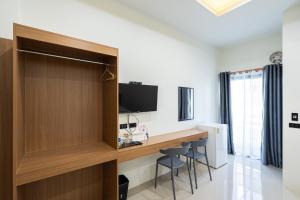 a room with a desk with a television and chairs at T-OneHome in Phetchabun