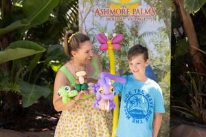 Eine Frau, die neben einem Jungen steht, der ausgestopfte Tiere hält. in der Unterkunft Ashmore Palms Holiday Village in Gold Coast