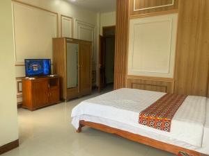 1 dormitorio con 1 cama y TV. en Khách sạn Việt Hoàng, en Bảo Lạc