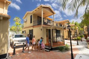uma família a andar em frente a uma casa em Ashmore Palms Holiday Village em Gold Coast