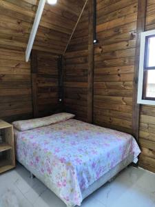 ein Schlafzimmer mit einem Bett in einem Holzzimmer in der Unterkunft Casa - Chalé da praia in Pontal do Paraná