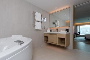 a bathroom with a tub and a sink and a mirror at New World Millennium Hong Kong Hotel in Hong Kong