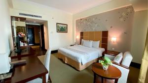 a hotel room with a bed and a table and a desk at Emerald Garden International Hotel in Medan