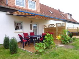 un patio con sedie rosse e un tavolo su una casa di Ferienwohnungen Hohen Niendorf bei Kühlungsborn a Hohen Niendorf