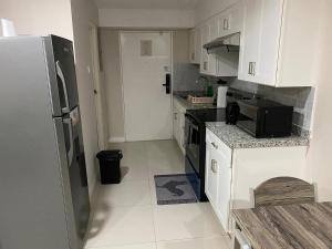 una cucina con armadietti bianchi e frigorifero nero di Finest Accommodation Bay Front Apt # 609 a Greencastle