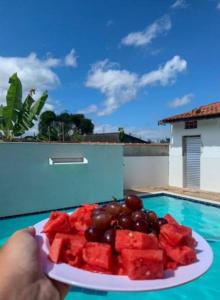 een persoon met een bord watermeloen en druiven bij Casa com piscina in Peruíbe