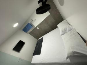 a bedroom with a white bed with a black pillow at Quarto privativo com banheiro compartilhado,a 800mts do pátio do forró in Caruaru