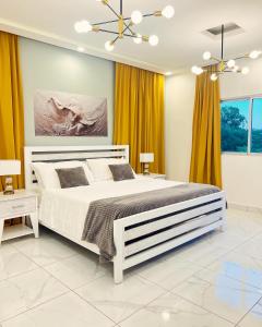 a bedroom with a large white bed and yellow curtains at 5 Star Villa minutes from Airport and Beaches in Sosúa