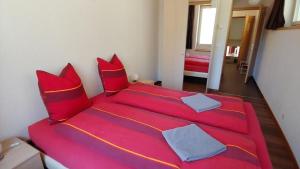un grande letto rosso con cuscini rossi in una stanza di Wohnung mit 3 Schlafzimmern Wylerdümen a Innertkirchen