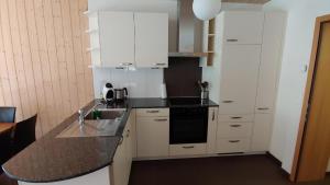 cocina con armarios blancos y encimera negra en Wohnung mit 3 Schlafzimmern Wylerdümen en Innertkirchen