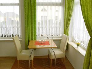 Ferienwohnungen Haus Mecklenburg في Elmenhorst: غرفة طعام مع طاولة وكراسي ونوافذ