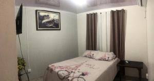 ein kleines Schlafzimmer mit einem Bett und einem Bild an der Wand in der Unterkunft Apartamento BYES in Quepos